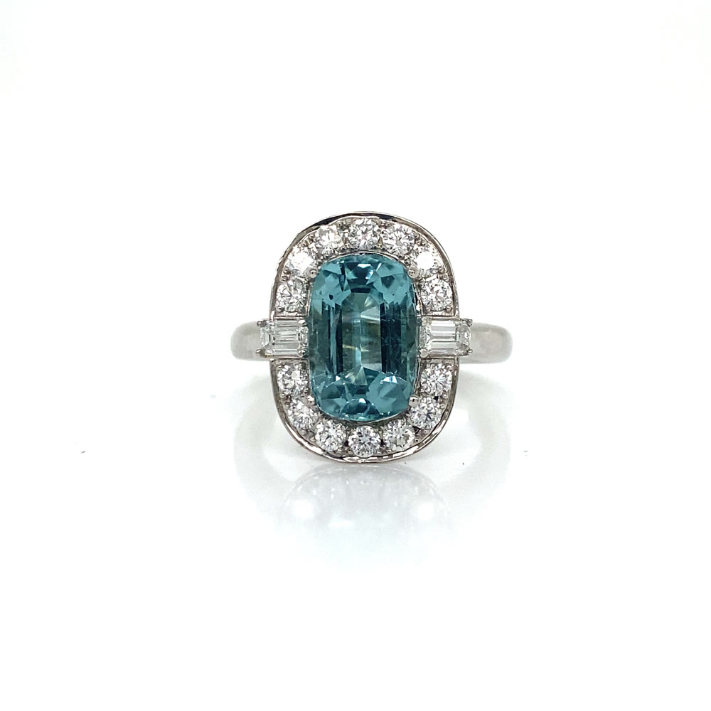 A blue stone ring surrounded by a bright halo and stepped side stones