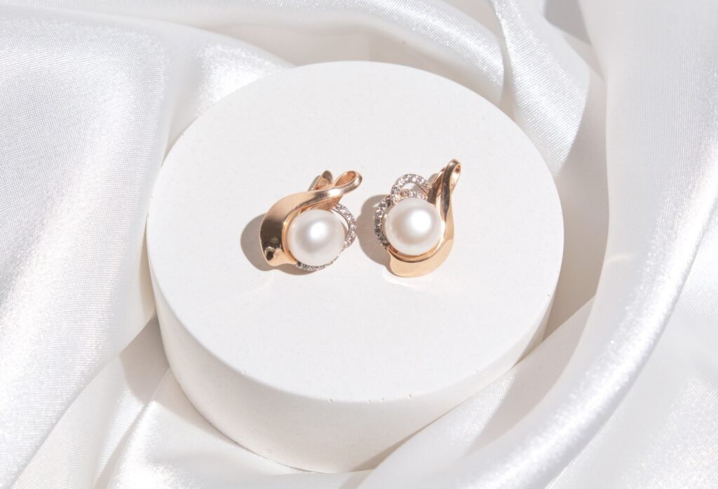 Gold earring with pearl on podium